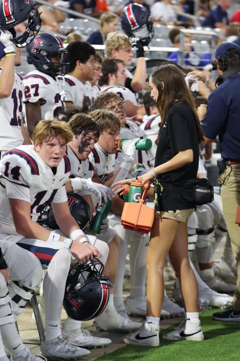 Athletic trainer passes out water bottles to exhausted football players after a tiring game. Athletic trainers prioritize the health of each sport player. 